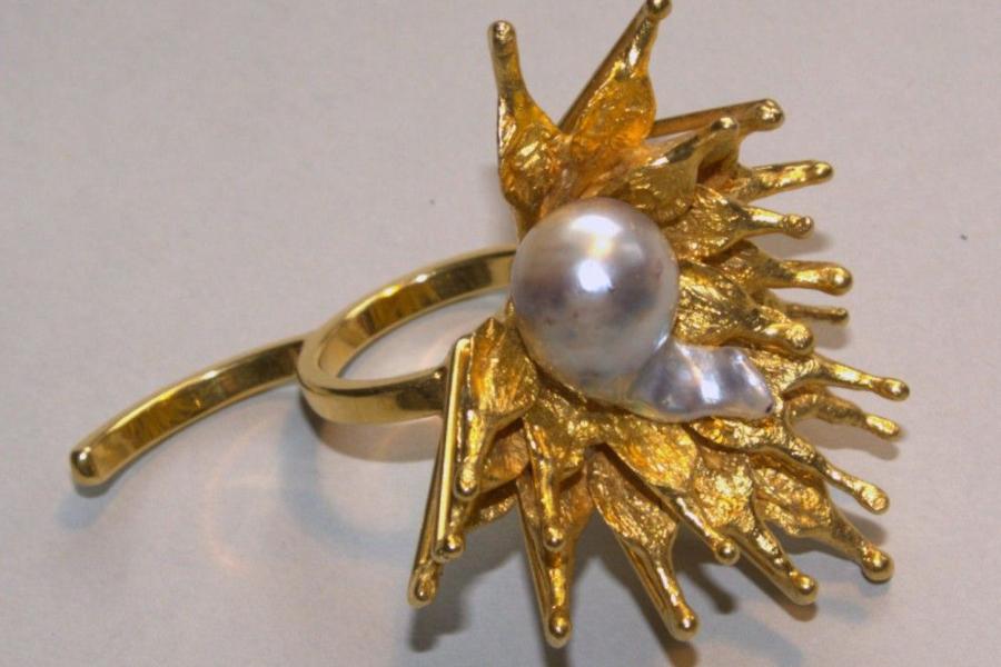 448  Si und Gerd Schulz, Extravaganter Ring in Form einer Distel, Gelbgold und graue Perle Stilisierte Blätter aus Gelbgold umgeben eine tropfenförmige graue Perle, 585 Gelbgold, gest., Gesamtgewicht: 27g, Dm. 4 …  (Schätzpreis: € 1.200, Startpreis: € 450,-)