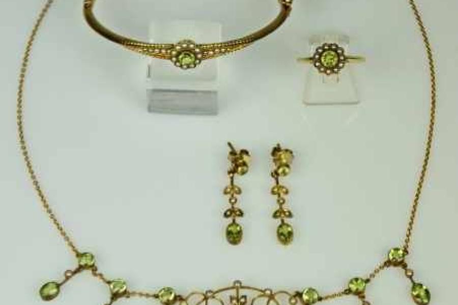 PARÜRE fünfteilig, Jugendstil: Collier, Ring in Blütenform, Paar Ohrgehänge, Armreif, jeweils besetzt mit Orientperlen und geschliffenen Peridotsteinen in Goldfassung. Mindestpreis:	850 EUR