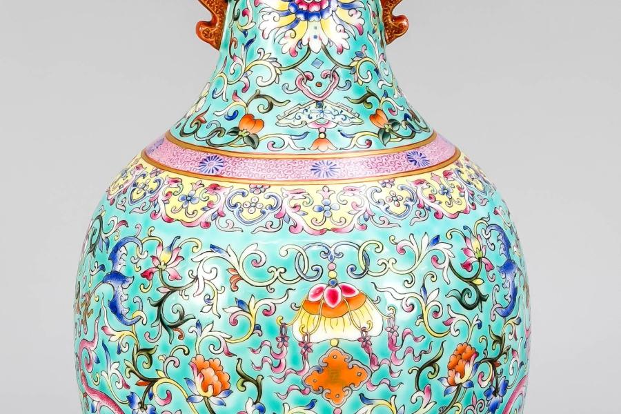 Famile-Rose Vase, China, wohl 19. Jh. Flaschenvase mit eingezogenem Lippenrand und durchbrochen gearbeiteten Handhaben als stilisierte Tierdarstellungen. Dekor in Famille-Rose vor türkisem Fond mit Lotusblüten und -Ranken, Fledermäusen, Drachen und kleinen Kartuschen aus stilisierten Wolkenbändern. Partiell goldstaffiert. Unter dem Boden eine geschriebene Jiaqing-Siegelmarke in Eisenrot vor türkisem Grund, minimal ber., H. 31 cm Startpreis 1.800 EUR