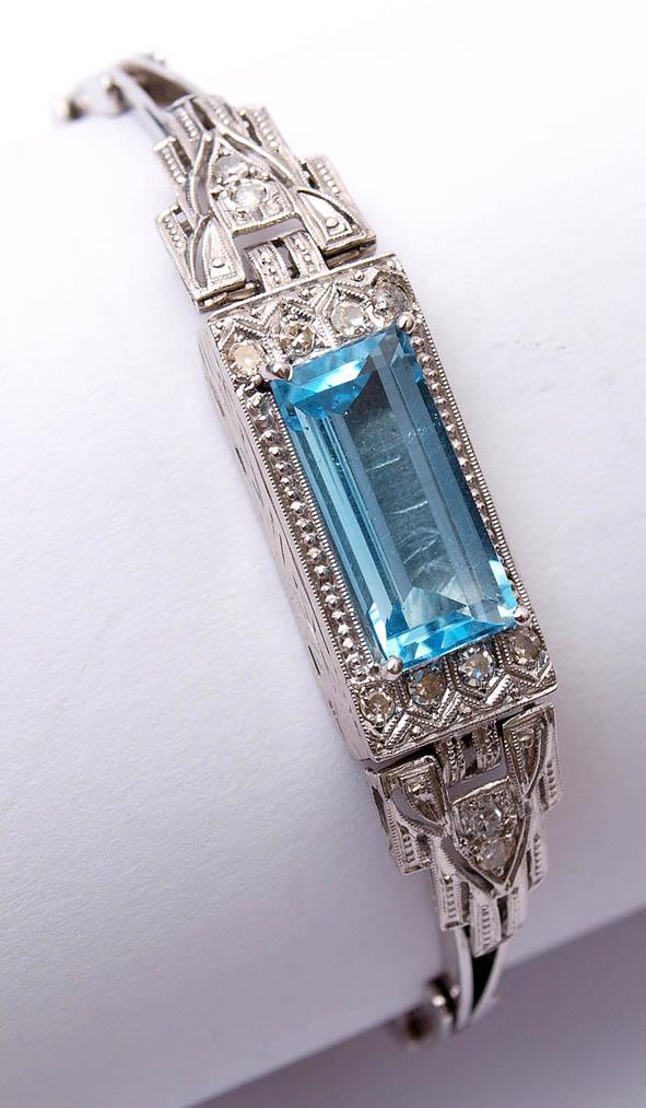 Losnummer: 644 Artikelnummer: 1812-104  Aquamarinarmband, 30er Jahre WG 18kt. Ährenförmiges Band, Mittelstück mit rechteckigem Aquamarin von feiner Farbe (ca. 6,5ct), umgeben von zwölf Brillanten von zus. ca. 0,15ct.  Ausrufpreis: € 2500,-