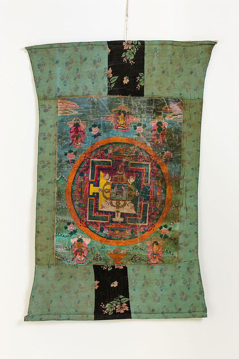 Thangka Tibet, wohl 18. Jh.Mischtechnik, goldgehöht. Mandala mit Schutzgottheiten  (Alterssp.). Eingefasst in Brokatstoff. 64 x 48,5 cm.(e6925013)	800,-- EURO